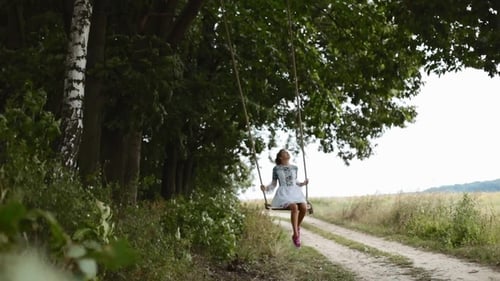 Cheerful, Smiling Girl in a White Dress Sway, Relax on Wooden Garden Swing.