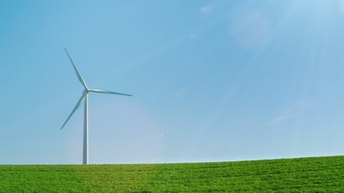 An Idyllic Picture of Pure Energy - a Wind Generator on a Green Hill in the Rays of the Sun