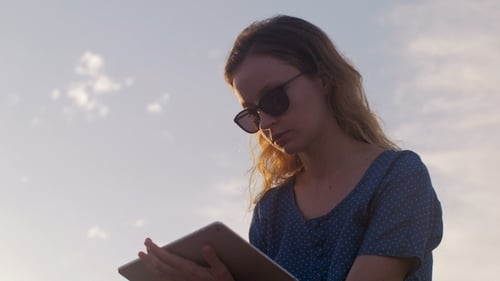 Mujer está usando tableta, tiro estático en el fondo del cielo nocturno