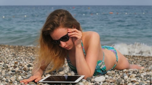 Woman Relaxes on Beach with Tablet