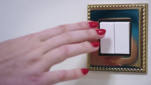 Mão de mulher desligando a luz na parede branca no interior do quarto aconchegante