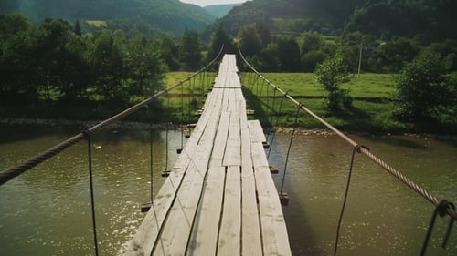 Puente de cuerda de tensión con cubierta de madera sobre el arroyo de la montaña