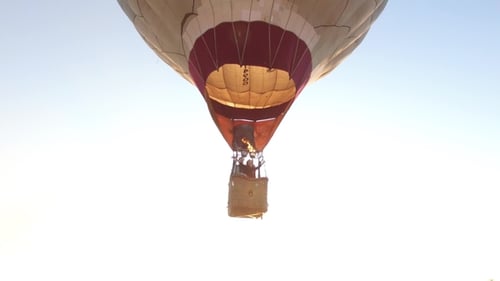 Hot Air Balloon Is Flying at Sunrise, Aerial View. Footage. White Hot Air Balloon in the Sunrise Sky