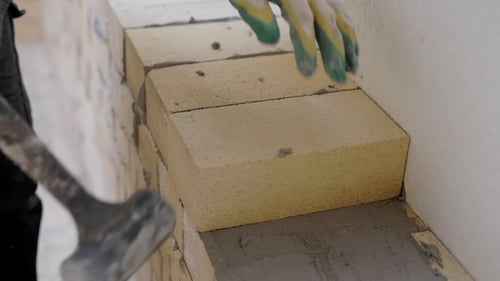 Foto del constructor colocando ladrillos en el mortero en interiores