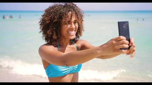 Cheerful Ethnic Woman Taking Selfie on Beach
