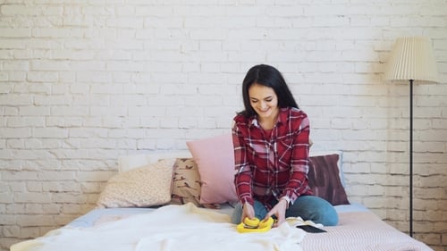 Mixed Race Woman Listening To Music on Headphones in Bed