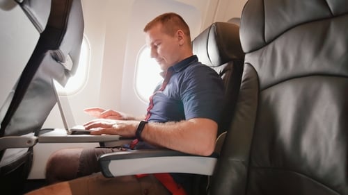 Man Working on Laptop During Airplane Flight