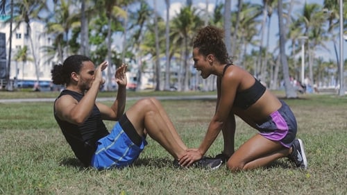 Woman Helping Exercising To Man