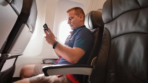 A Young Man in the Plane Before Departure Writes the Text in His Mobile Phone.