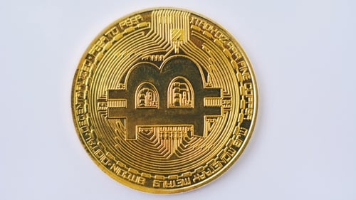 Aufnahme von goldenem Bitcoin rotierend auf weißem Hintergrund