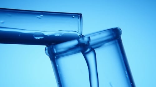 Blue Water Flows From a Narrow Tube Into a Wide One in a Scientific Lab