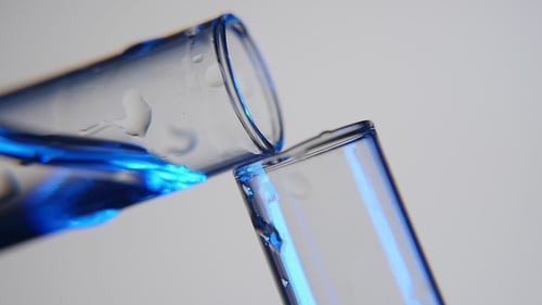 Shining Liquid Is Poured From One Tube Into Another in a Medical Laboratory