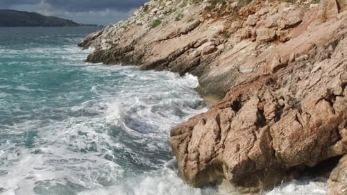 The Waves Breaking on a Stony Beach, Forming a Spray. Footage Splashing Waves on the Rocks of the