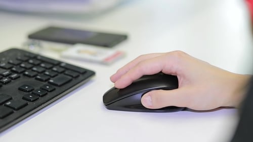 Woman's Hand Using Cordless Mouse on White Table