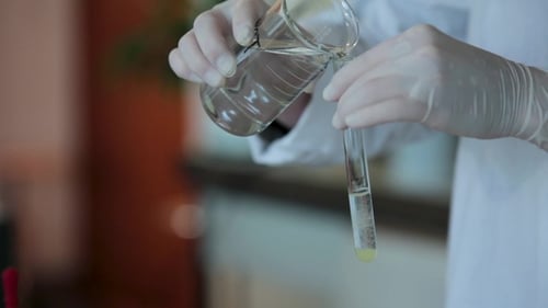 Scientist Hand Pouring a Chemical Solution From a Laboratory Glass Test Tube Into a Scientific
