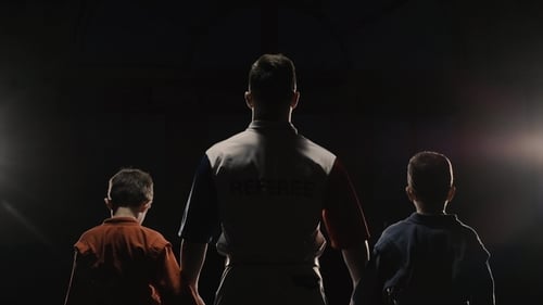 Rear View of the Boys Athletes and Referee Who Raises the Hand of the Winner. The Referee Raises the