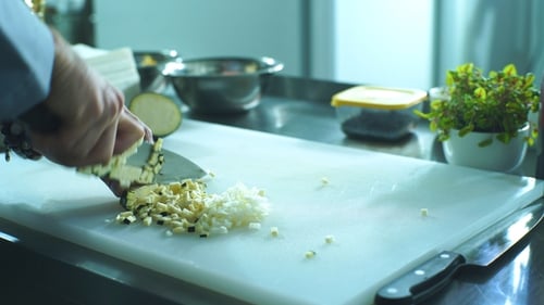 Ein professioneller Koch schneidet mit einem Messer schnell Auberginen auf dem Brett