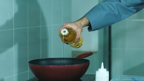 Chef Pouring Oil in to the Frying Pan for Cooking