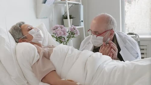 Doctor Holds Patient's Hand in Hospital Room