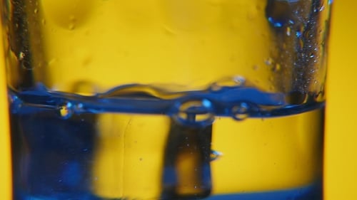 Five Big Cubes of Ice Are Thrown Into a Crystaline Glass with Fresh Water in Studio