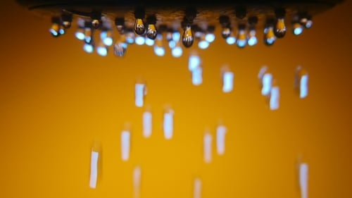 Flashing Droplets Fall Slowly From a Shower Nozzle in a Brown Bathtub