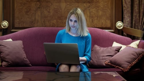 Beautiful Woman Sitting on Luxury Sofa and Working on Notebook Computer
