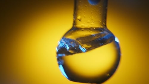 Distilled Water with Blue Tints Is Shaken in a Round Bottom Flask in a Scientific Lab