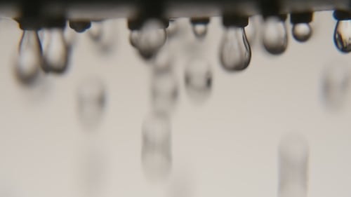 Crystal Clear Water Blobs Fall From a Shower Nozzle in a Blue Bathroom