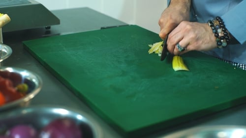 Cook Dices Vegetable on Cutting Board in Kitchen