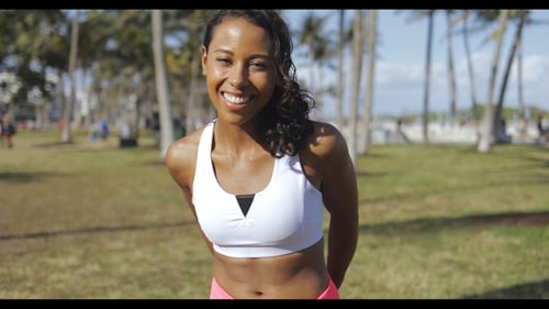 Smiling Woman Stretching Arms in Sunny Urban Park