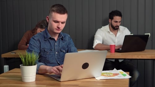 Workers Typing on Laptops in a Shared Office