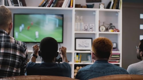 Multi-ethnic Men Celebrate Goal Together. Back View. Excited Fans Watch Football Game on the Couch