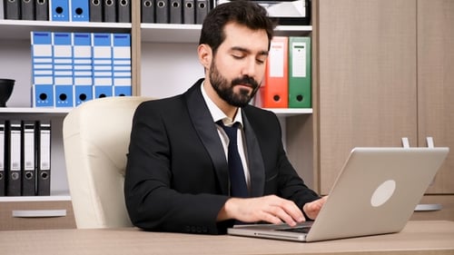 Confident Businessman Working at Laptop in Modern Office