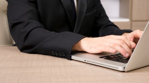 Man Typing on Laptop in Office Setting