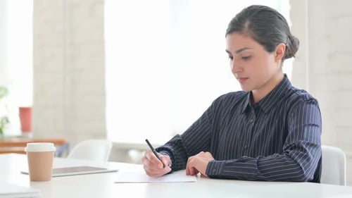 Woman Writing on Paper at Bright Office Desk