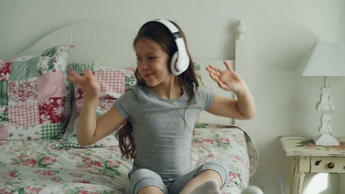 Girl Dancing with Headphones in Bedroom