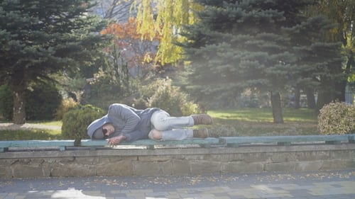 Young Homeless Boy Sleeping on the Street Bench
