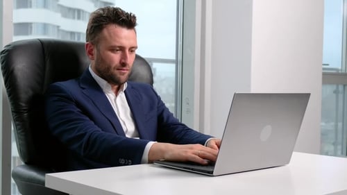 Businessman in Formal Wear Using Laptop in Office