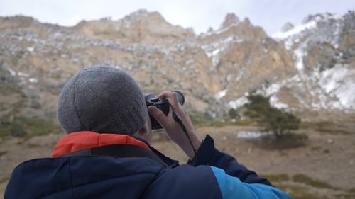 Photographer in Mountains Takes Pictures of Snowy Peaks