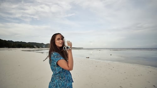 A Young Russian Girl with Happy Emotions Is Walking Along the Beach and Posing
