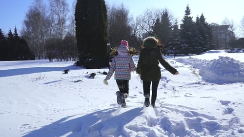 Happy Family Mother and Baby Girl Daughter Run Playing in Winter Outdoors in the Snow