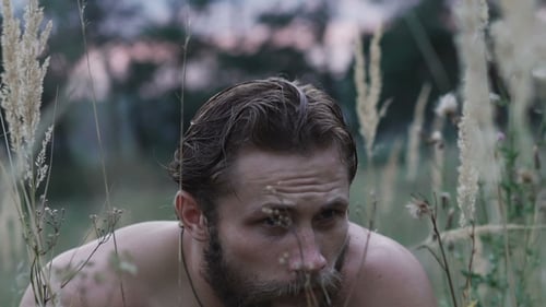 Homme barbu de peur regardant autour de lui dans l'herbe de la steppe
