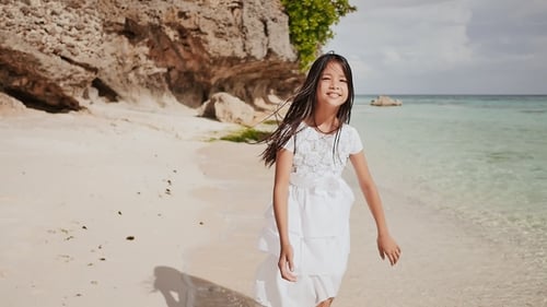 A Charming and Happy Philippine Teenage Girl in a White Summer Dress Is Running Along a Tropical