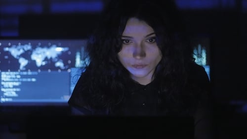 Joven programadora trabajando en una computadora en el centro de datos llena de pantalla