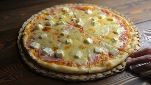 Hot Pizza Being Sliced on Wooden Table