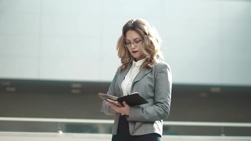 Blonde Woman in Business Attire Reads Notebook