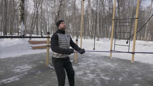 Man Exercising with Resistance Band in Snowy Park