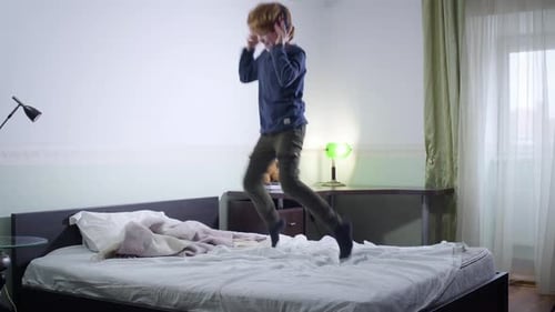 Young Adult Jumps on Bed with Headphones