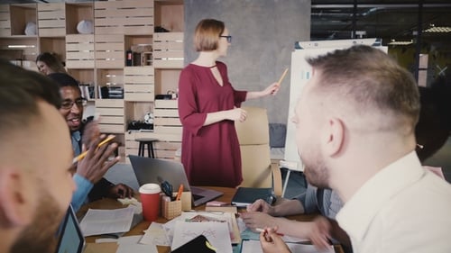 Woman Presenting Business Charts to Colleagues in Office