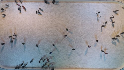 People Are Skating on Illuminated Ice Rink in the Evening